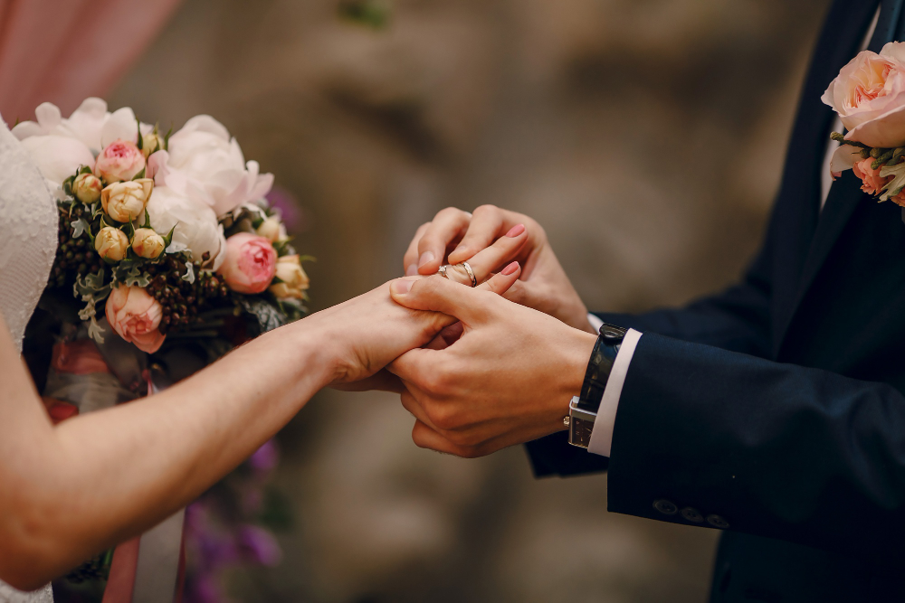 Photograph of a couple exchanging wedding rings