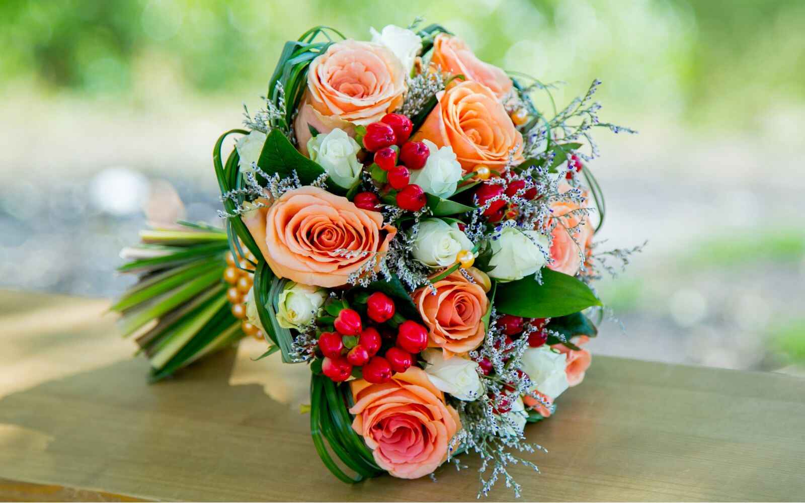 Bouquet de fleurs de mariage éclatant avec des roses orange et des baies rouges, apportant une touche colorée et chaleureuse à la cérémonie.