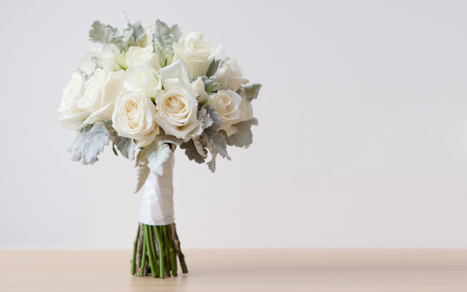 Élégant bouquet de fleurs de mariage composé de roses blanches et de feuillage argenté, parfait pour une cérémonie raffinée